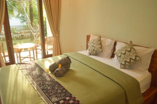 a bedroom with a bed and a balcony with a view at Maja House Penida in Nusa Penida
