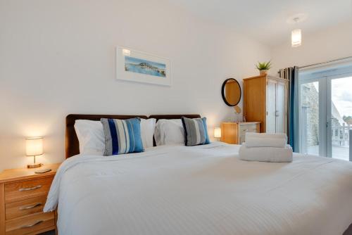 a bedroom with a large white bed with a window at Hannafore Lemain Garden Apts in Looe