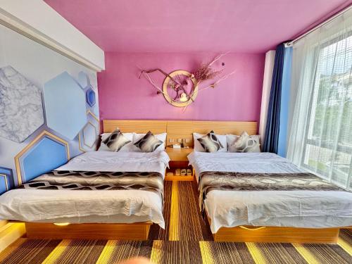 two beds in a room with pink walls at Earstring Hanging Gardens Hotel in Dali Ancient Town
