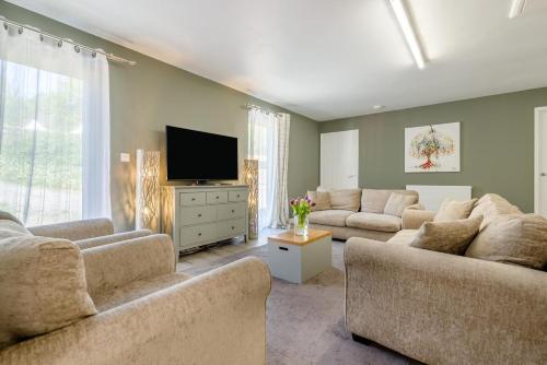 a living room with two couches and a flat screen tv at Magnolia - Bude in Bude