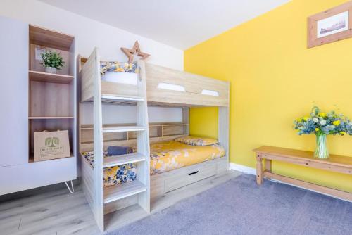 a bedroom with a bunk bed and a yellow wall at Magnolia - Bude in Bude