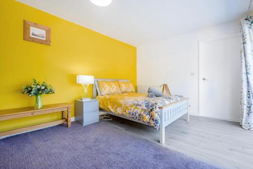 a bedroom with a bed and a yellow wall at Magnolia - Bude in Bude