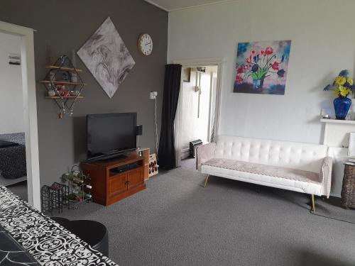 a living room with a white couch and a television at Ellie's Villa in Brydone