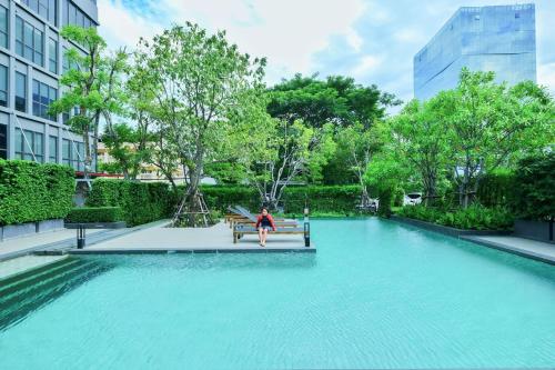 a woman sitting on a bench in a pool of water at Siamese Residence Sukhumvit 87 Bangkok in Bangkok