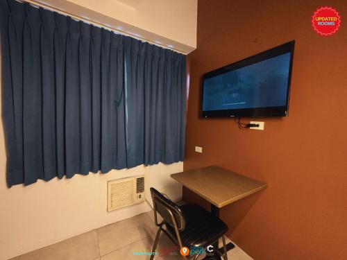 a room with a desk and a television on a wall at Citizen Hotel in Manila