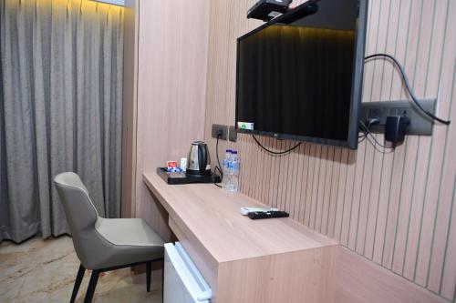 a room with a desk with a television and a chair at Vivaan Inn in Vijayawāda
