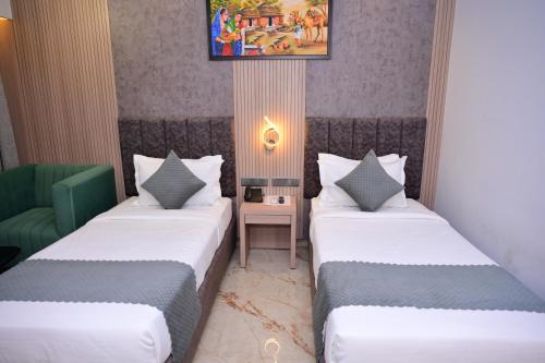 a room with two beds and a table with a lamp at Vivaan Inn in Vijayawāda