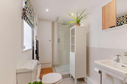 a white bathroom with a toilet and a sink at Cheriton Coastal Cottage in Deal