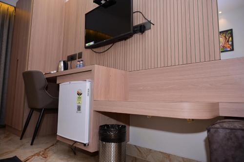a room with a desk with a television and a small refrigerator at Vivaan Inn in Vijayawāda