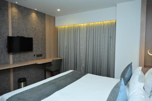 a hotel room with a bed and a flat screen tv at Vivaan Inn in Vijayawāda