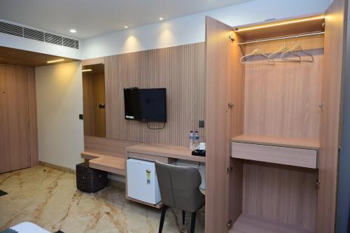 a hotel room with a desk and a television at Vivaan Inn in Vijayawāda