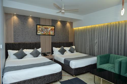 a hotel room with two beds and a chair at Vivaan Inn in Vijayawāda