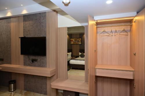 a hotel room with a television and a bedroom at Vivaan Inn in Vijayawāda