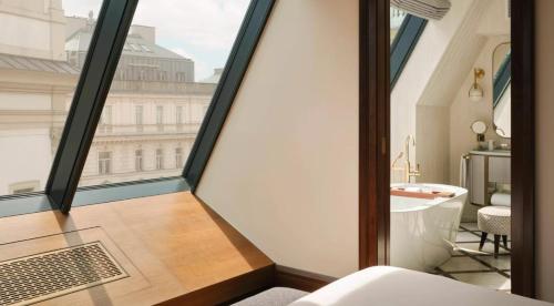 a room with a large window and a bathroom with a tub at Rosewood Vienna in Vienna