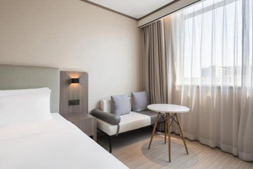 a hotel room with a bed and a chair and a window at Hanting Hotel Beijing Fangshan Longhu Paradise Walk in Beijing