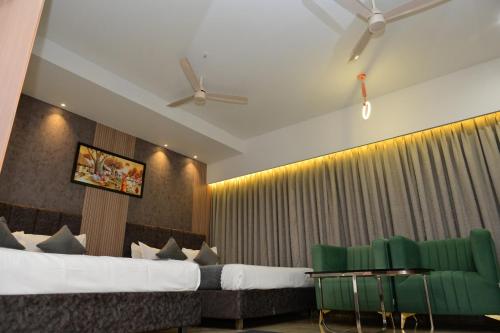 a bedroom with a bed and two green chairs at Vivaan Inn in Vijayawāda