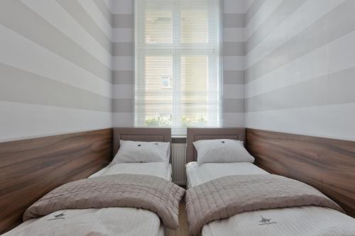 two beds in a room with a window at Apartamenty4you - Apartamenty Atlantic in Sopot