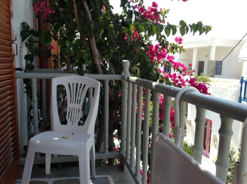 a white chair sitting on a porch with pink flowers at Arian Hotel in Parikia