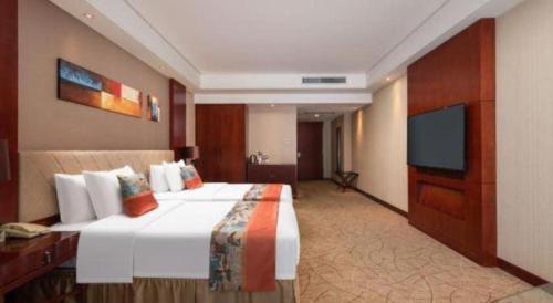 a hotel room with a large bed and a flat screen tv at Wuhan Soluxe Hotel in Wuhan