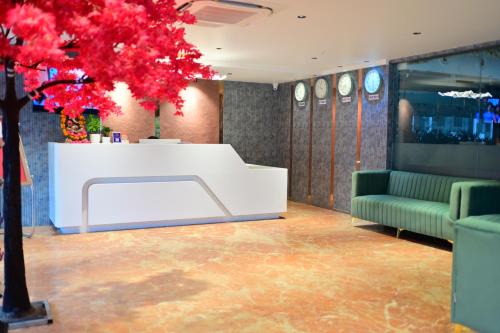 a lobby with a white table and a red tree at Vivaan Inn in Vijayawāda