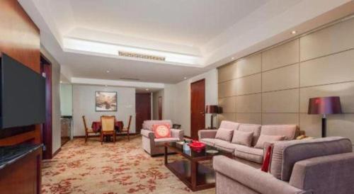 a living room with couches and a flat screen tv at Wuhan Soluxe Hotel in Wuhan