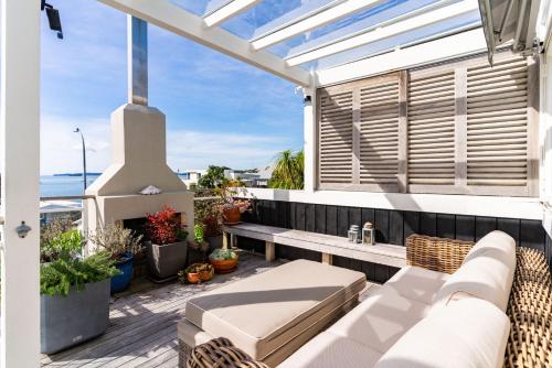 a balcony with a couch and a fireplace at Oli Kai - Algies Bay Holiday Home in Matakana