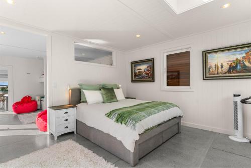 a white bedroom with a bed and a window at Oli Kai - Algies Bay Holiday Home in Matakana