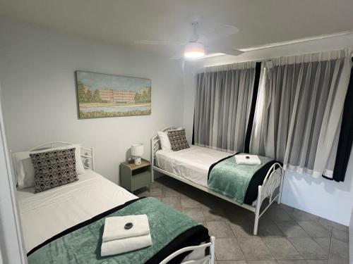a bedroom with two beds and a window at Excellsior Apartments in Mooloolaba