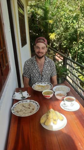 a man sitting at a table with plates of food at Daresh home stay in Maskeliya