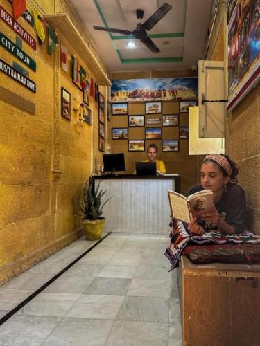 a woman sitting at a counter reading a book at Heritage Haveli Jaisalmer in Jaisalmer