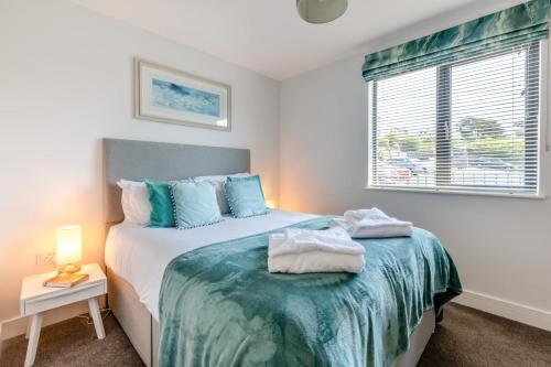 a bedroom with a bed with blue pillows and a window at Beach Haven - C6 in Woolacombe