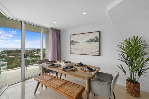 a dining room with a table and chairs and a window at Beachside Penthouse w Private Rooftop & Oceanviews in Caloundra