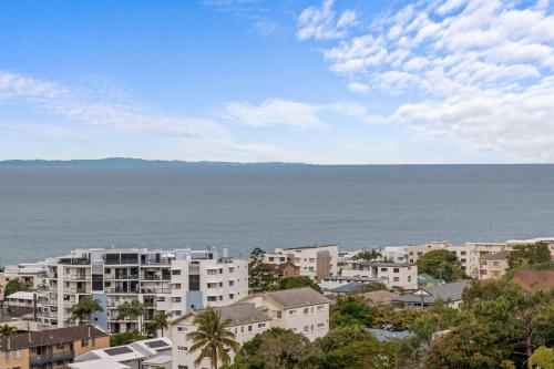 a city with buildings and the ocean in the background at Beachside Penthouse w Private Rooftop & Oceanviews in Caloundra