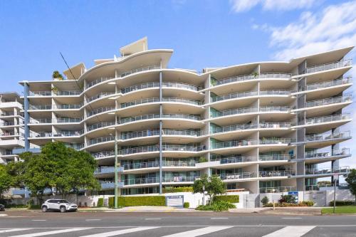 a large apartment building with balconies on a street at Beachside Penthouse w Private Rooftop & Oceanviews in Caloundra