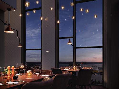 a restaurant with tables and chairs and a large window at KUST Hotell & SPA in Piteå