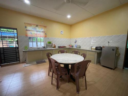 a kitchen with a table and chairs and a refrigerator at Baitul Hikmah Fi Homestay in Batu Pahat
