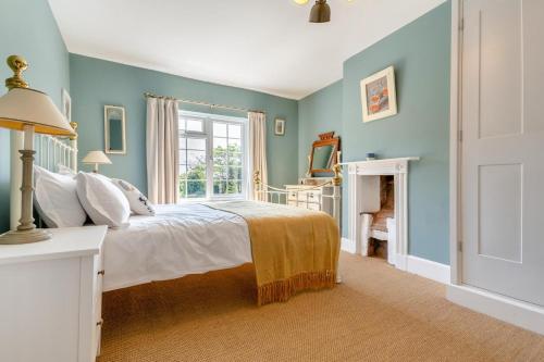 a blue bedroom with a bed and a window at The Southend Cottage in Ledbury