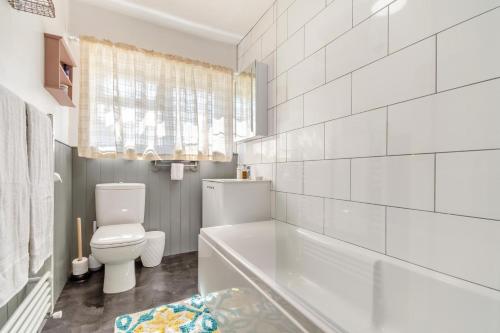 a white bathroom with a tub and a toilet at The Southend Cottage in Ledbury