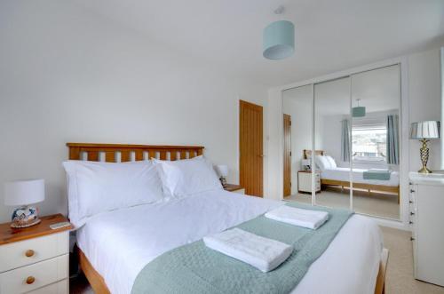 Un dormitorio con una gran cama blanca con espejo. en Autumn Leaves, en Ilfracombe