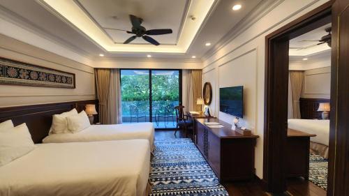 a hotel room with two beds and a television at Silk Path Grand Sapa Resort & Spa in Sa Pa