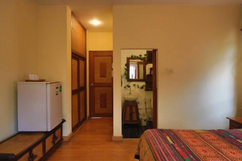 a room with a bed and a bathroom with a refrigerator at Plumeriahome near Chiangmai Airport in Chiang Mai