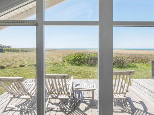 a porch with rocking chairs and a view of the ocean at Panoramic Seaside Escape - By Traum Ferienwohnungen in Lønstrup