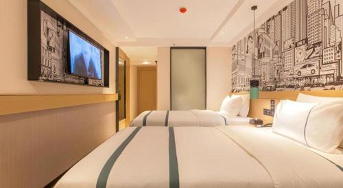 a hotel room with two beds and a flat screen tv at City Comfort Inn Wuhan International Expo Center Yongwang in Wuhan