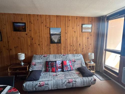 ein Schlafzimmer mit einem Bett und einer Holzwand in der Unterkunft Appartement au pied des pistes à Super Besse - FR-1-814-61 in Besse-et-Saint-Anastaise
