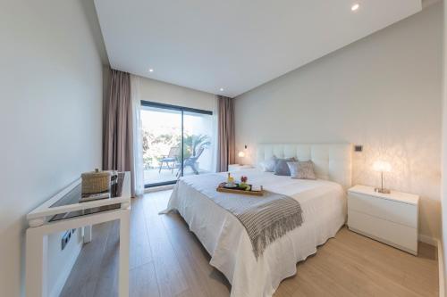 a bedroom with a large bed and a large window at NOA Apartment Quinta do Lago in Quinta do Lago