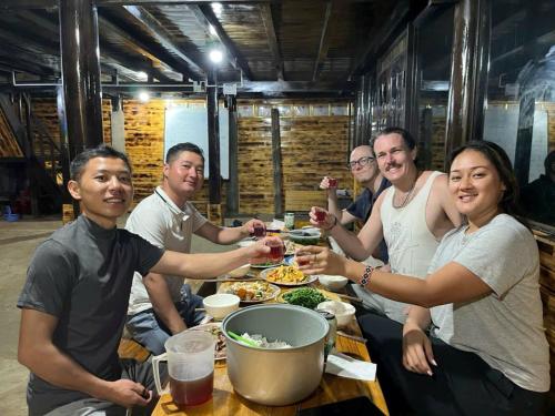 a group of people sitting around a table eating food at Sapa Guide Homestay & Trekking in Lao Cai