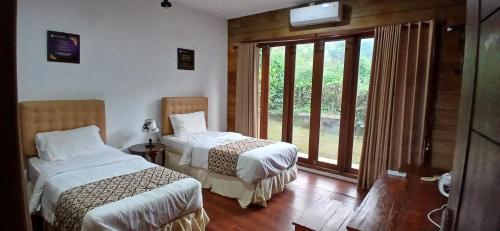 a bedroom with two beds and a window at Giri Tengah Resort Borobudur in Ngargoremo