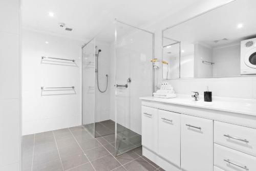 a white bathroom with a shower and a sink at Northwind Beachfront Apartments in Mooloolaba