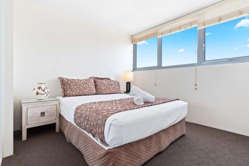 a white bedroom with a bed and a window at Northwind Beachfront Apartments in Mooloolaba