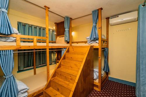 a room with three bunk beds and a staircase at Kwabahal Garden Hostel in Kathmandu